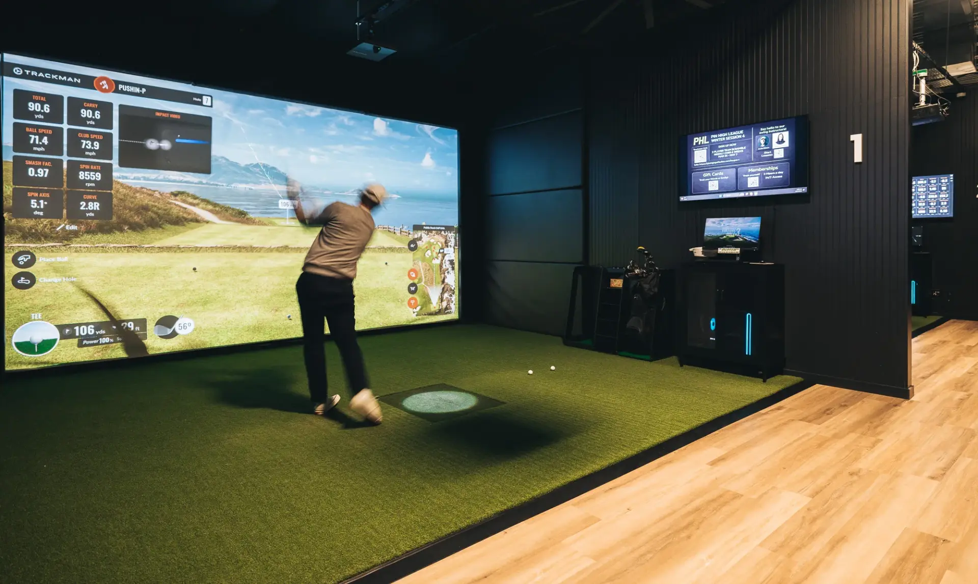 A golfer mid-swing in Bay 1 at Pin High Golf Suites, hitting into a wall-size TrackMan simulator screen
